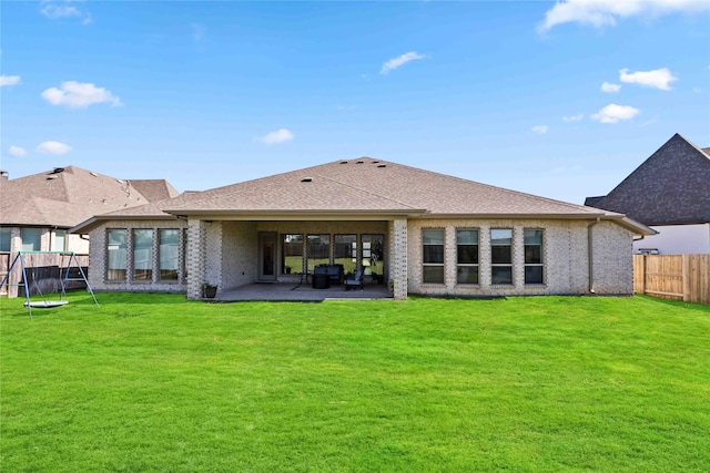 back of house featuring a yard, a patio, and a trampoline