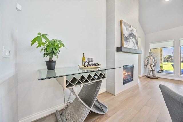 interior space with hardwood / wood-style flooring, lofted ceiling, and a tiled fireplace