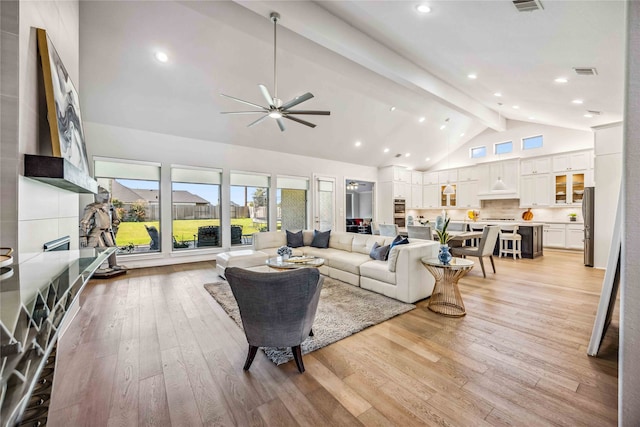 living room with ceiling fan, beam ceiling, high vaulted ceiling, and light hardwood / wood-style flooring