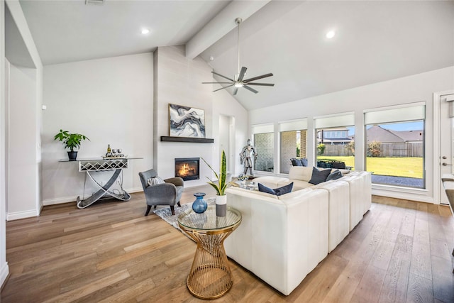 living room with ceiling fan, a large fireplace, beam ceiling, and light hardwood / wood-style floors