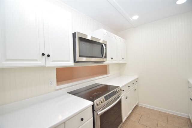 kitchen with appliances with stainless steel finishes, light tile patterned floors, and white cabinets