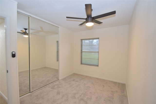 unfurnished bedroom featuring a closet, light colored carpet, and ceiling fan