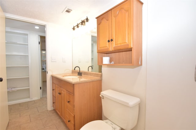 bathroom with toilet, vanity, and tile patterned floors