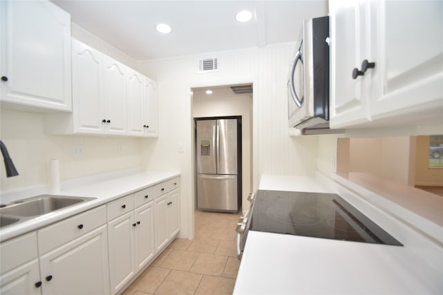 kitchen with white cabinets, sink, ornamental molding, light tile patterned flooring, and appliances with stainless steel finishes