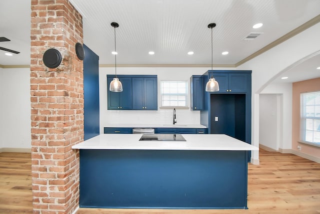 kitchen featuring decorative light fixtures, blue cabinets, tasteful backsplash, sink, and ornamental molding