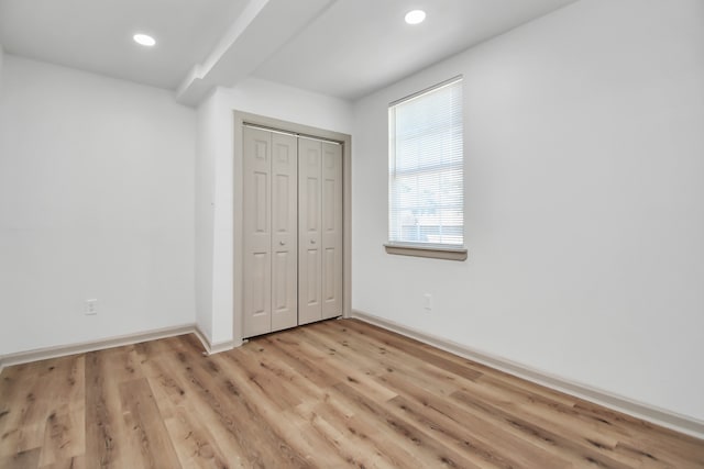 unfurnished bedroom with light wood-type flooring and a closet