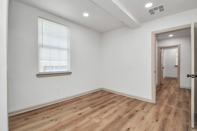 unfurnished room featuring beamed ceiling and hardwood / wood-style floors