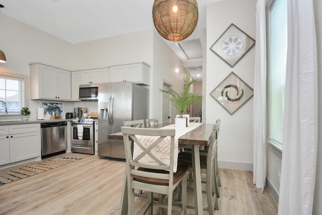 kitchen featuring stainless steel appliances, white cabinets, light hardwood / wood-style floors, and decorative backsplash