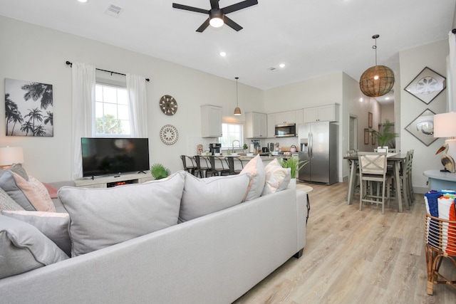 living room with sink, ceiling fan, and light wood-type flooring