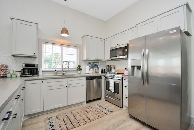 kitchen featuring hanging light fixtures, white cabinetry, appliances with stainless steel finishes, and sink