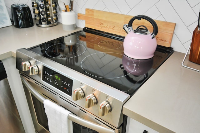 interior details with decorative backsplash and stainless steel range with electric cooktop