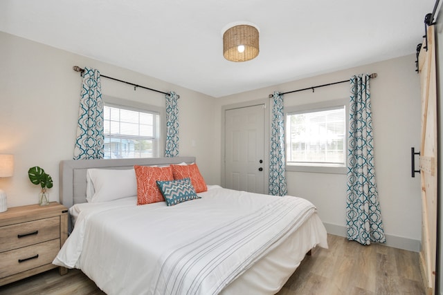 bedroom featuring hardwood / wood-style flooring, a barn door, and multiple windows