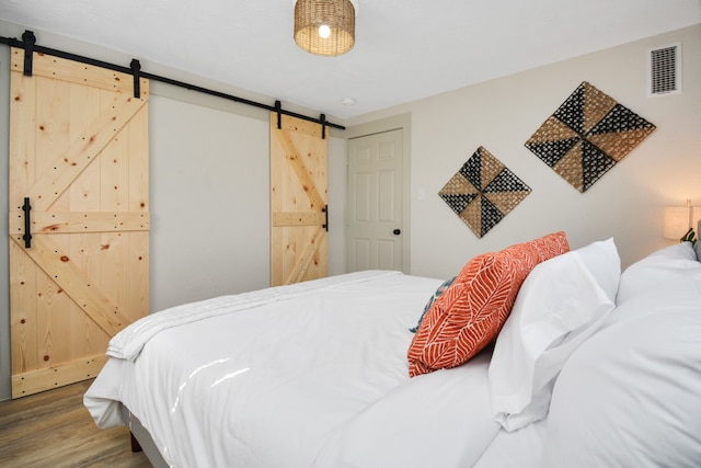 bedroom with hardwood / wood-style floors and a barn door