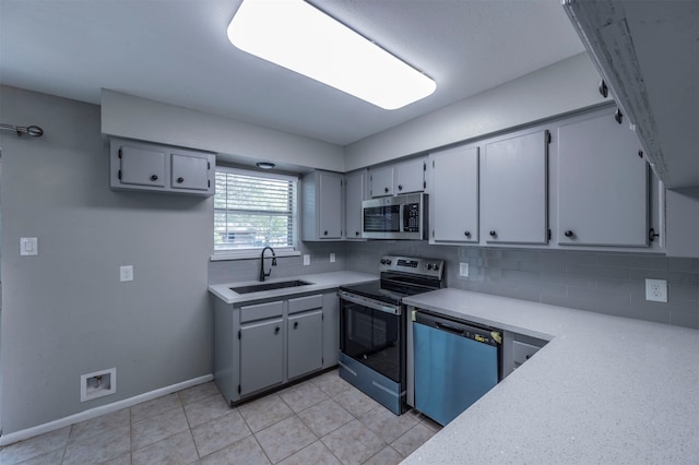 kitchen with stainless steel appliances, sink, tasteful backsplash, and gray cabinetry