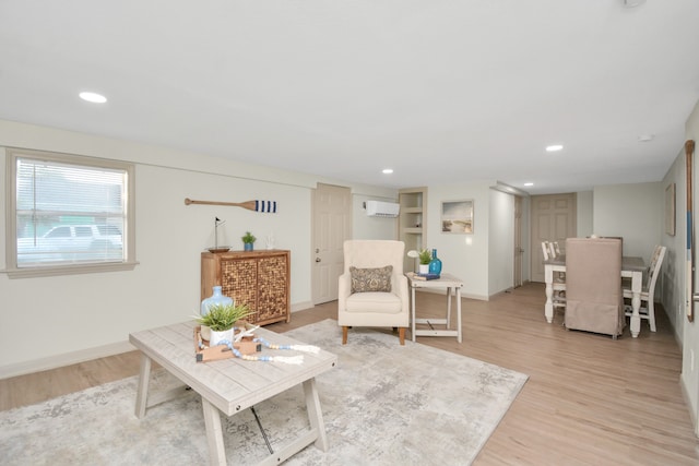 living area with a wall mounted AC and light hardwood / wood-style floors