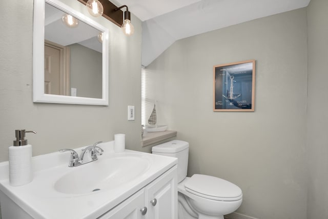 bathroom with toilet, vanity, and vaulted ceiling