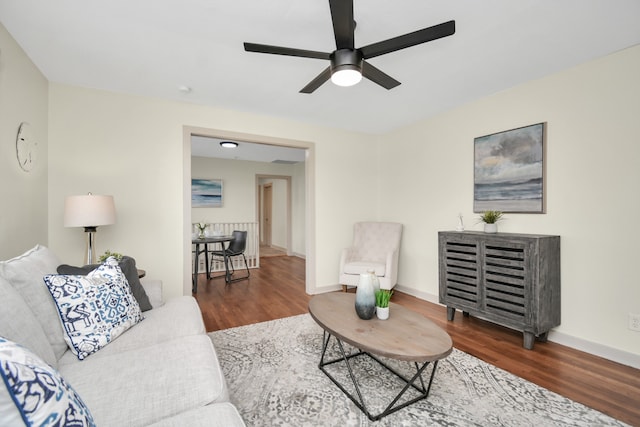 living room with dark wood-type flooring and ceiling fan