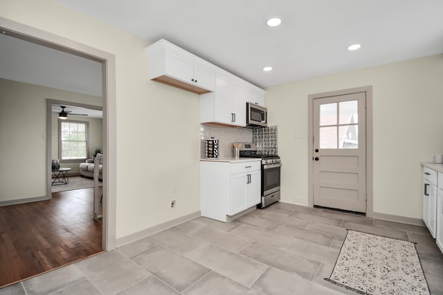 kitchen with white cabinets, light wood-type flooring, appliances with stainless steel finishes, and tasteful backsplash