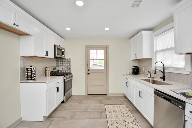 kitchen featuring white cabinets, decorative backsplash, stainless steel appliances, and sink