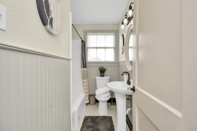 bathroom with tile patterned flooring, shower / bath combo, and toilet