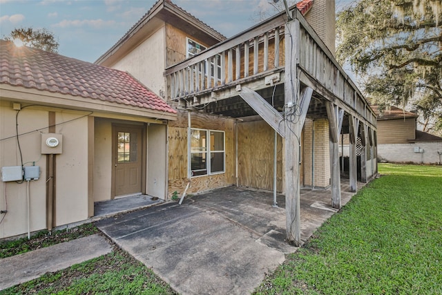 back of property featuring a lawn, a balcony, and a patio area