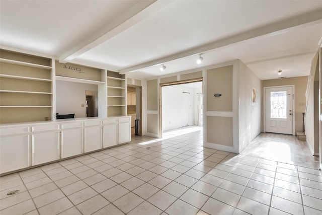 unfurnished living room with beam ceiling, light tile patterned floors, and built in shelves