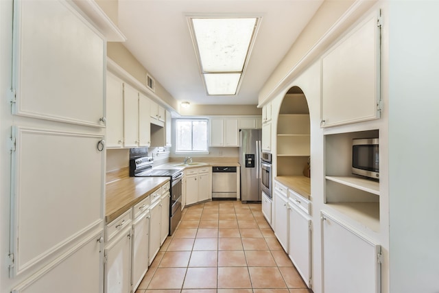 kitchen featuring white cabinets, sink, light tile patterned flooring, and stainless steel appliances