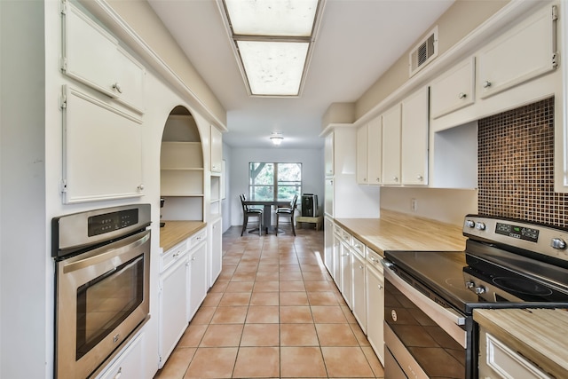 kitchen with backsplash, white cabinetry, appliances with stainless steel finishes, and light tile patterned floors