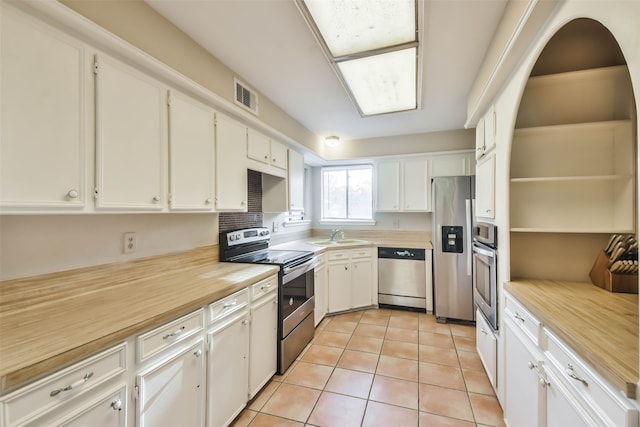 kitchen with white cabinets, light tile patterned flooring, sink, and appliances with stainless steel finishes