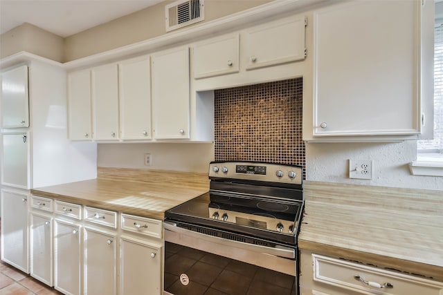 kitchen with wooden counters, white cabinetry, light tile patterned floors, and electric stove