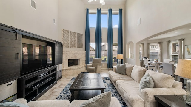 living room featuring a fireplace, a high ceiling, a wealth of natural light, and ceiling fan