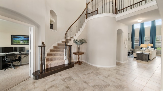 stairs featuring carpet and a high ceiling