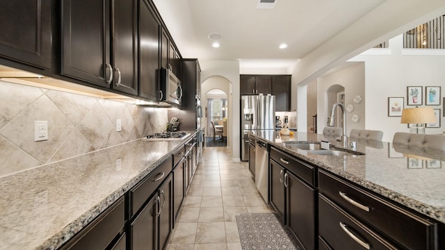 kitchen featuring sink, light tile patterned floors, tasteful backsplash, dark brown cabinetry, and stainless steel appliances