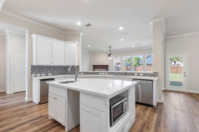 kitchen with a center island with sink, white cabinets, sink, hardwood / wood-style flooring, and appliances with stainless steel finishes