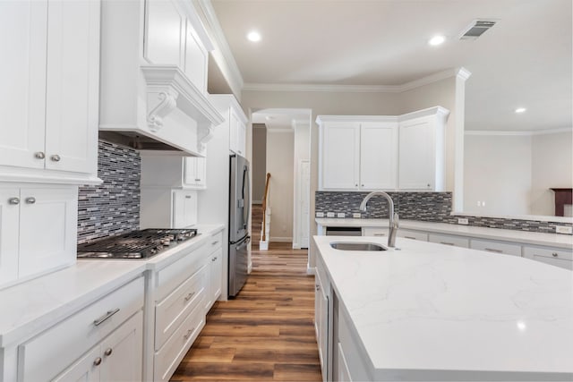 kitchen with decorative backsplash, appliances with stainless steel finishes, light stone counters, dark hardwood / wood-style floors, and white cabinetry