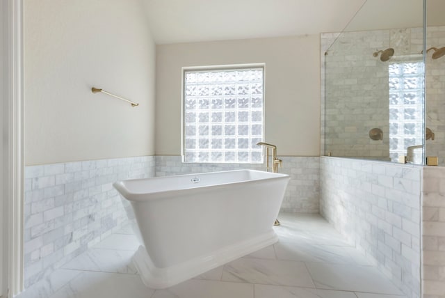 bathroom featuring plus walk in shower and tile walls