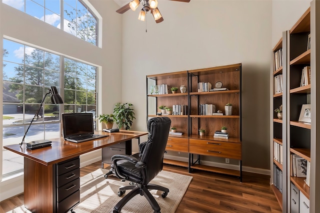 office space with ceiling fan, a towering ceiling, and dark wood-type flooring