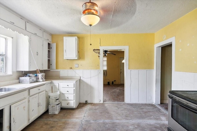 kitchen with ceiling fan, sink, white cabinets, and a textured ceiling