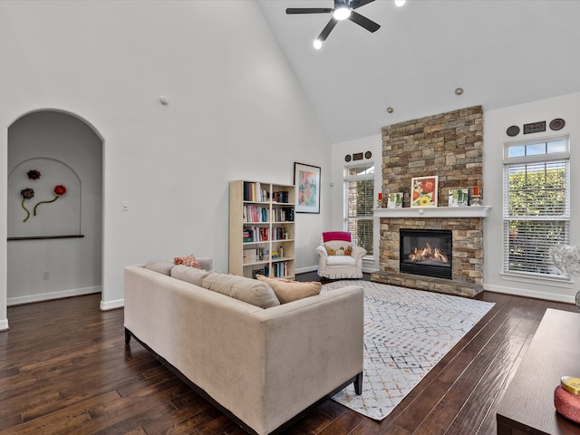 living room with a stone fireplace, ceiling fan, high vaulted ceiling, and dark hardwood / wood-style floors