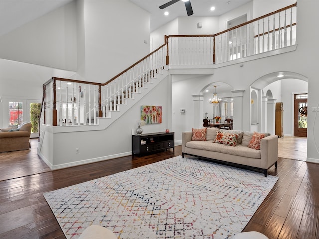 living room featuring high vaulted ceiling, ceiling fan with notable chandelier, and dark hardwood / wood-style floors