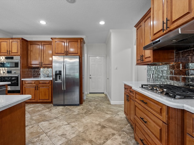 kitchen with appliances with stainless steel finishes, light stone countertops, a textured ceiling, backsplash, and crown molding