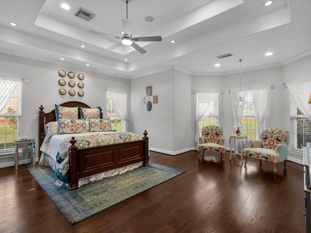 bedroom featuring ornamental molding, ceiling fan with notable chandelier, dark hardwood / wood-style flooring, and a tray ceiling