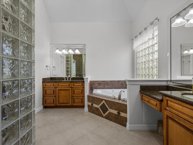 bathroom featuring tile patterned flooring, lofted ceiling, vanity, and a relaxing tiled tub