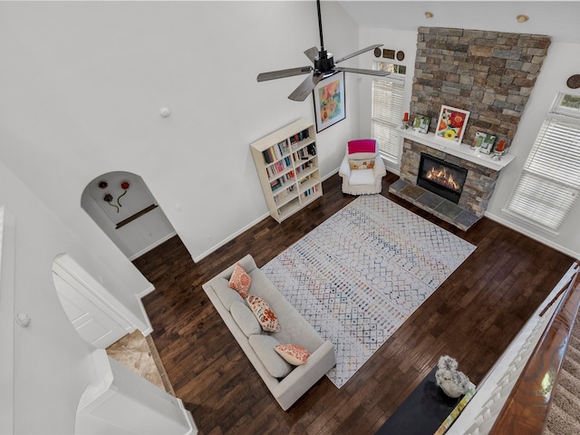 living room with dark wood-type flooring, high vaulted ceiling, ceiling fan, and a fireplace