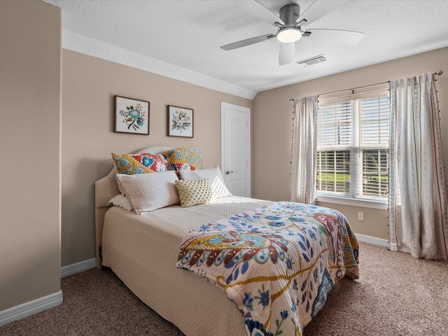 carpeted bedroom featuring ceiling fan and a textured ceiling