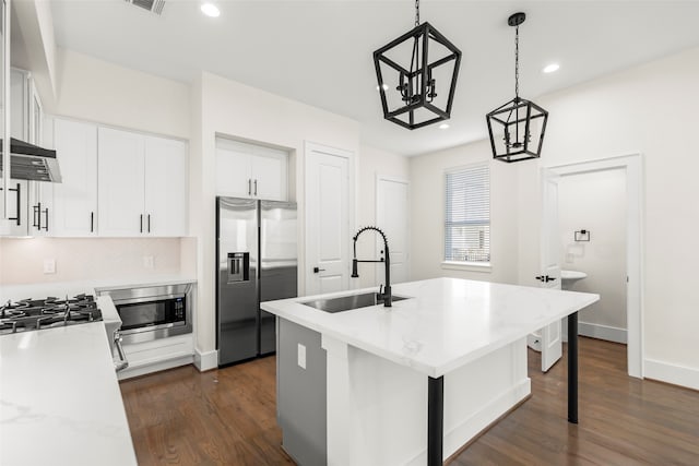 kitchen with sink, hanging light fixtures, stainless steel appliances, a center island with sink, and white cabinets