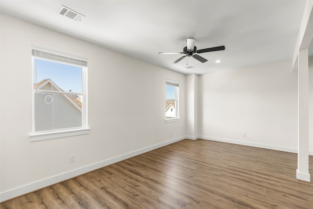 empty room with ceiling fan, plenty of natural light, and wood-type flooring