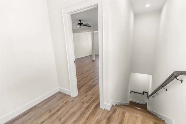 stairs featuring ceiling fan and hardwood / wood-style flooring