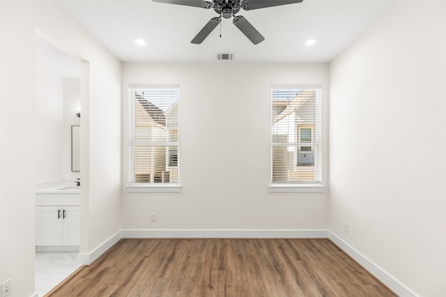 unfurnished room featuring hardwood / wood-style floors, ceiling fan, and sink