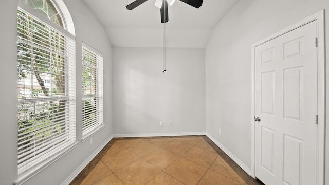 tiled empty room with ceiling fan and vaulted ceiling